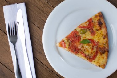 Mozzarella peynirli, domatesli, fesleğenli ve yeşil zeytinli pizza. Pizza dilimi beyaz tabakta servis edilir. Soda ve limon. Gurme Fotoğrafı