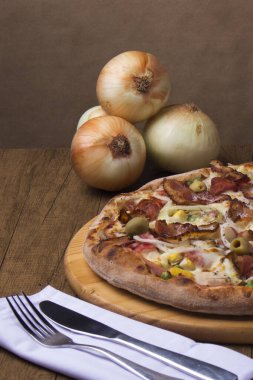 Portekiz pizzasının enfes bir fotoğrafı. Arka planda kırsal soğanlar ve çatal bıçak takımı kullanılmaya hazır. Pizzacılar ve restoranlar.