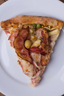 Tabakta servis edilen pizza dilimi. Jambon, bezelye yumurtası, palmiye, pepperoni, soğan, mozzarella ve pastırmadan yapılmış Portekiz pizzası. Bir dilim pizzanın makro fotoğrafı..
