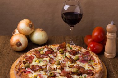 Jambon, bezelye yumurtası, palmiye, pepperoni, soğan, mozzarella ve pastırmadan yapılmış Portekiz pizzası. Yemeğe eşlik etmesi için bir kadeh kırmızı şarap..