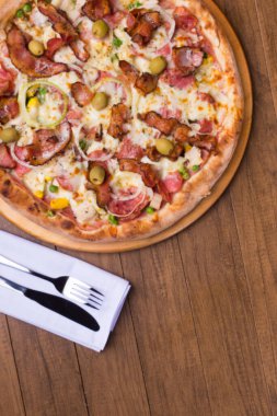 Lezzetli Portekiz pizzası jambon, bezelye yumurtası, palmiye, pepperoni, soğan, mozzarella ve pastırmadan yapılmış. Tahta tahtada servis edilmiş. Metinler için alt boşluğu olan üstte yakın plan fotoğraf.