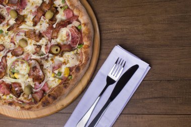 Jambon, bezelye yumurtası, palmiye, pepperoni, soğan, mozzarella ve pastırmadan yapılmış Portekiz pizzası. Tahta tahtada servis edilmiş. Sağ taraftaki metin için boşluğu olan en üstteki fotoğraf.