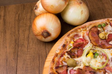 Lezzetli Portekiz pizzası, ahşap bir tahtanın üzerinde, kırsal soğanla servis ediliyor. Metin veya illüstrasyonlar için boşluk bırakıldı.