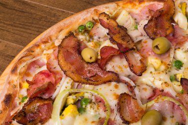 Jambon, bezelye yumurtası, palmiye, pepperoni, soğan, mozzarella ve pastırmadan yapılmış Portekiz pizzası. Sağ alt köşede yemek sıralı yakın plan fotoğraf..