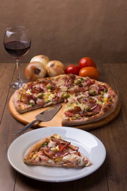 Jambon, bezelye yumurtası, palmiye, pepperoni, soğan, mozzarella ve pastırmadan yapılmış Portekiz pizzası. Dikey gastronomik fotoğrafçılık. Pizza servisi. Kırmızı şarap eşlik edecek..