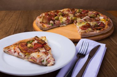 Jambon, bezelye yumurtası, palmiye, pepperoni, soğan, mozzarella ve pastırmadan yapılmış Portekiz pizzası. Çatal bıçak. Gurme fotoğrafçılık. Restoranlar ve Pizzacılar.