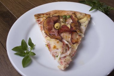 Tabakta servis edilen pizza dilimi. Jambon, bezelye yumurtası, palmiye, pepperoni, soğan, mozzarella ve pastırmadan yapılmış Portekiz pizzası. Süslemek için fesleğen yaprakları. Restoranlar ve Pizzacılar.