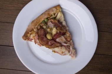 Tabakta servis edilen pizza dilimi. Jambon, bezelye yumurtası, palmiye, pepperoni, soğan ve mozzarella ve pastırmadan yapılmış Portekiz pizzası..