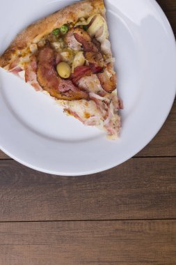 Tabakta servis edilen pizza dilimi. Jambon, bezelye yumurtası, palmiye, pepperoni, soğan, mozzarella ve pastırmadan yapılmış Portekiz pizzası. Metinler için alt boşluğu olan yakın plan fotoğraf.