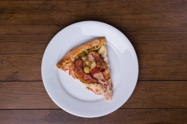 Tabakta servis edilen pizza dilimi. Jambon, bezelye yumurtası, palmiye, pepperoni, soğan, mozzarella ve pastırmadan yapılmış Portekiz pizzası. Görüntünün ortasına yerleştirilmiş elementlerle üst çekim.