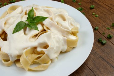 Beşamel soslu ve fesleğen yapraklı Tagliatelle makarnası. Beyaz soslu makarna. Makarna mutfağının yakın çekim fotoğrafı.