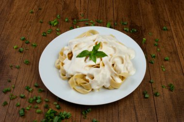 Beşamel soslu ve fesleğen yapraklı Tagliatelle makarnası. Beyaz soslu makarna..