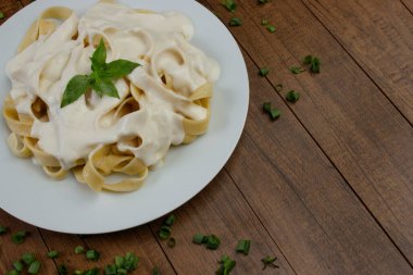 Beşamel soslu ve fesleğen yapraklı Tagliatelle makarnası. Beyaz soslu makarna. Makarna fotografı. Metin için boş alanı olan fotoğraf.