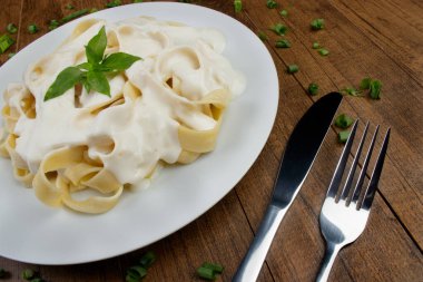 Beşamel soslu ve fesleğen yapraklı Tagliatelle makarnası. Beyaz soslu makarna. Üst görüntü fotoğrafı. Mesaj için yer var. Siyah arkaplan