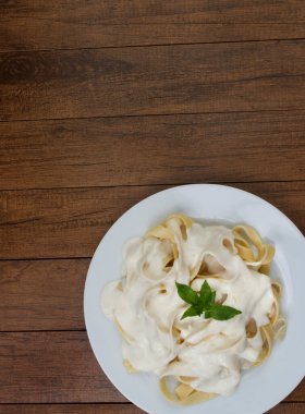 Beşamel soslu ve fesleğen yapraklı Tagliatelle makarnası. Beyaz soslu makarna. Metin için üst görünüm alanı olan en üstteki resim.