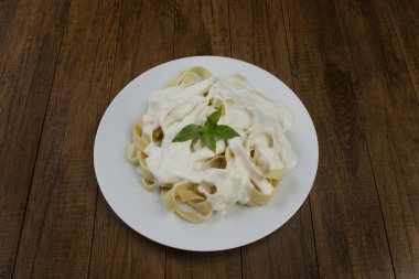 Beşamel soslu ve fesleğen yapraklı Tagliatelle makarnası. Beyaz soslu makarna. Üst görüntü fotoğrafı. Mesaj için yer var. Siyah arkaplan