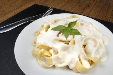 Bechamel Sauce ve Basil Leaves ile servis edilen Lezzetli Tagliatelle Pasta. Beyaz soslu makarna..
