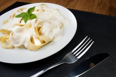Bechamel Sauce ve Basil Leaves ile servis edilen Lezzetli Tagliatelle Pasta. Beyaz soslu makarna. Tüm dünyada popüler olan tipik İtalyan yemekleri..