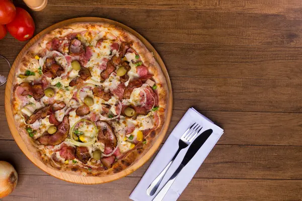 Lezzetli Portekiz pizzası jambon, bezelye yumurtası, palmiye, pepperoni, soğan, mozzarella ve pastırmadan yapılmış. Tahta tahtada servis edilmiş. Üst yakın plan fotoğraf. Metinler ve grafik sanatları için boşluk.