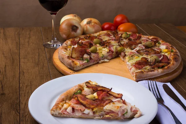 Jambon, bezelye yumurtası, palmiye, pepperoni, soğan, mozzarella ve pastırmadan yapılmış Portekiz pizzası. Tabakta servis edildi. Gastronomi fotoğrafı..