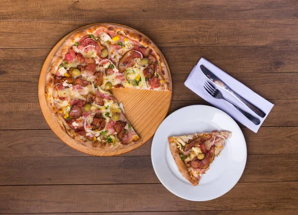 Jambon, bezelye yumurtası, palmiye, pepperoni, soğan, mozzarella ve pastırmadan yapılmış Portekiz pizzası. Tabakta pizza dilimi. Üst fotoğraf. Restoranlar ve Pizzacılar.