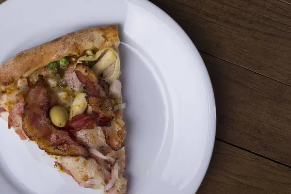 Tabakta servis edilen pizza dilimi. Jambon, bezelye yumurtası, palmiye, pepperoni, soğan, mozzarella ve pastırmadan yapılmış Portekiz pizzası. Üst yakın plan fotoğraf. Sağdaki metinler için boşluk.