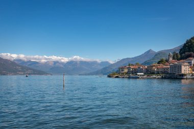 İtalya 'nın Como Gölü' ndeki ünlü Bellagio manzarası. Baharda mavi gökyüzüne karşı. Arka planda karlı dağlar var.