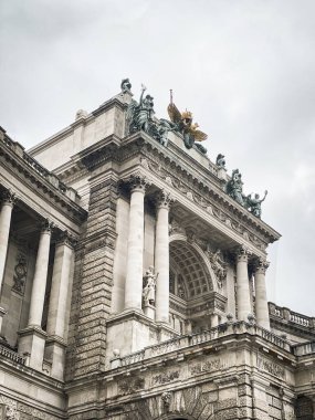 Bulutlu gökyüzüne karşı Hofburg Sarayı 'nın bir parçası olan Neue Burg' un girişinin alçak açılı görüntüsü