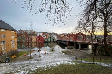 Norveç, Trondheim 'ın Brygge ilçesinde Nidelva Nehri' nin bulunduğu renkli tarihi kereste depoları ve kışın Eski Şehir Köprüsü veya Gamle Bybro