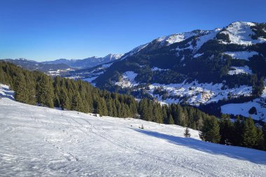 Avusturya 'nın Kleinwalsertal kentinde kışın mavi gökyüzüne karşı kayak bölgesinin manzarası