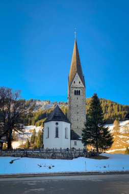 Kışın mavi gökyüzüne karşı Mittelberg, Kleinwalsertal, Avusturya 'nın kilise kökü