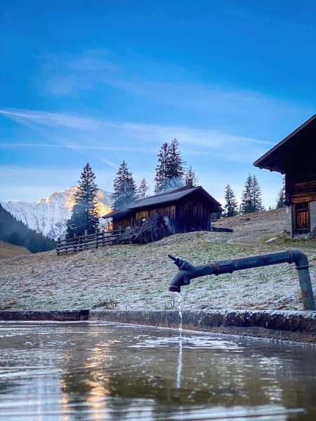 スイスのアルプスの古い伝統的な山小屋と青空に対して厳しい冬に流れる水の風景 — ストック写真