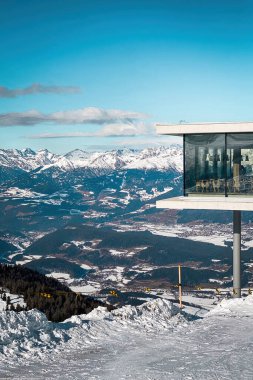 Plân de Corones, İtalya - 30 Ocak 2023: Kronplatz 'daki AlpiNN restoranı açık mavi gökyüzüne karşı güneşli bir günde, karlı Dolomitler' deki Plan de Corones kayak merkezinin önünde