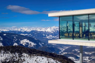 Plân de Corones, İtalya - 30 Ocak 2023: Kronplatz 'daki AlpiNN restoranı açık mavi gökyüzüne karşı güneşli bir günde, karlı Dolomitler' deki Plan de Corones kayak merkezinin önünde