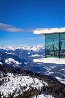 Plân de Corones, İtalya - 30 Ocak 2023: Kronplatz 'daki AlpiNN restoranı açık mavi gökyüzüne karşı güneşli bir günde, karlı Dolomitler' deki Plan de Corones kayak merkezinin önünde