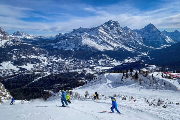 Kışın mavi gökyüzüne karşı Ampezzo Vadisi ve Monte Sorapiss Dağı ve Antelao 'nun panoramik manzarasıyla kayak yapan insanlar