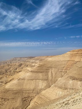 Mujib Kanyonu 'nda tortu tabakaları, Ürdün mavi gökyüzüne karşı bulutlar.