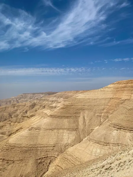 Mujib Kanyonu 'nda tortu tabakaları, Ürdün mavi gökyüzüne karşı bulutlar.