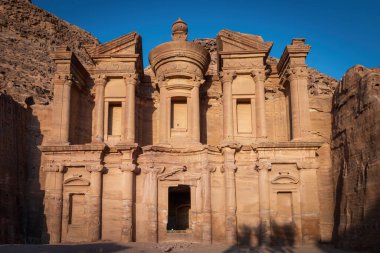 Ürdün 'ün tarihi ve arkeolojik kenti Petra' daki ünlü Ad Deir manastırı gün batımında mavi gökyüzüne karşı