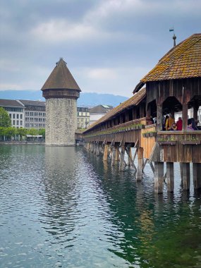 Bulutlu gökyüzüne karşı Reuss nehri, Chapel köprüsü ve su kulesi olan Lucerne şehrinin manzarası
