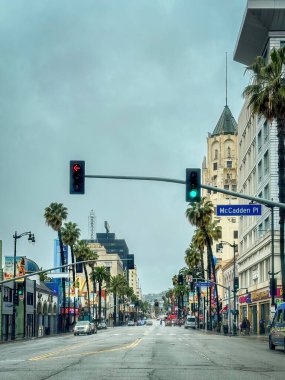 Los Angeles, ABD - 30 Mart 2024: Bulutlu gökyüzüne karşı Hollywood Bulvarı 'nda yükselen palmiyelerle sokak manzarası
