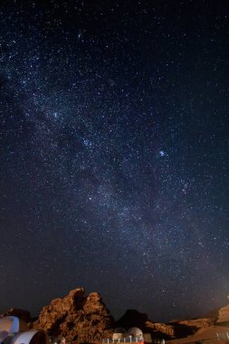Gece gökyüzü yıldızlarla dolu ve Wadi Rum Çölü 'nün üzerindeki samanyolu kısmen köpük çadırı ve kayalık manzarayla dolu.
