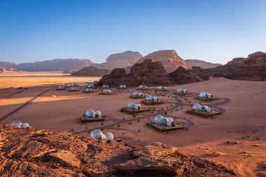 Güneş doğarken mavi gökyüzüne karşı Ürdün 'deki Wadi Rum Çölü' ndeki balon çadır kampının manzarası.