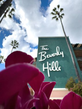 Beverly Hills, ABD - 31 Mart 2024: Berverly Hills 'in alçak açılı görüntüsü Beverly Hills Hotel, Kaliforniya' nın maskesinde bulutlu mavi gökyüzüne karşı bulanık harflerle yazıldı