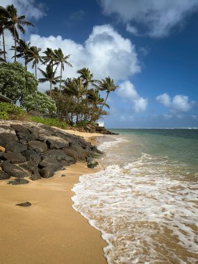 Oahu, Hawaii 'deki Kaaawa plajı, kuzeye bakan bulutlarla mavi gökyüzüne karşı.