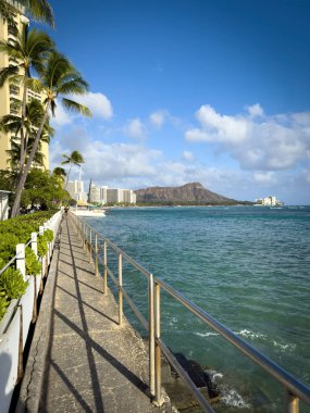 Waikiki Plajı Honolulu, Hawaii, ABD 'de sahil boyunca bulutlu mavi gökyüzüne karşı yürüyor