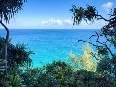 Kalalau Patikası, Kauai, Hawaii, ABD 'den görülen turkuaz renkli Pasifik Okyanusu manzaralı bulutlu mavi gökyüzüne karşı