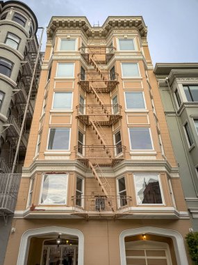 San Francisco, Kaliforniya 'daki bir binanın sarı cephesinde tipik bir Amerikan yangın merdiveni zikzak çiziyor.