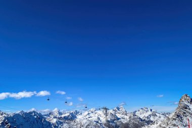 Oetztal Alplerinde ve Soelden kayak bölgesinde kar kaplı dağların önünde mavi gökyüzüne karşı kablo araba.