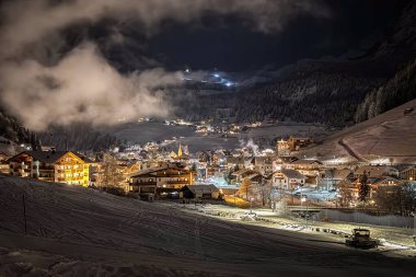 Val Gardena 'daki Grden Selva' daki aydınlanmış Wolkenstein manzarası gece karla kaplıydı..